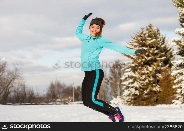 Winter fun people concept. Young girl jumping in the snow. Attractive lady wearing blue jumper and sporty leggins. . Young girl jumping in the snow.