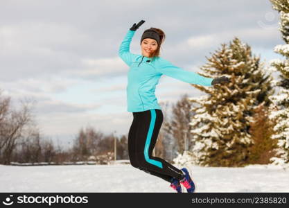 Winter fun people concept. Young girl jumping in the snow. Attractive lady wearing blue jumper and sporty leggins. . Young girl jumping in the snow.