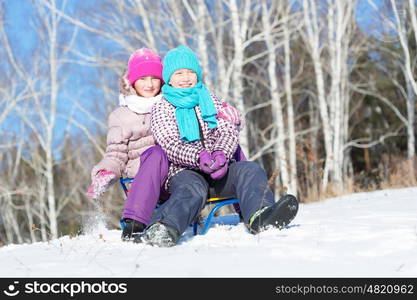 Winter fun. Two cute girls enjoying sledge ride in beautiful snowy winter park