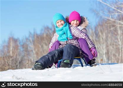 Winter fun. Two cute girls enjoying sledge ride in beautiful snowy winter park