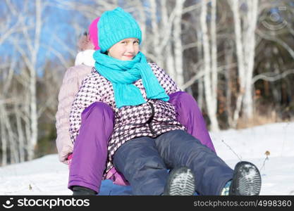 Winter fun. Two cute girls enjoying sledge ride in beautiful snowy winter park