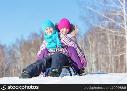 Winter fun. Two cute girls enjoying sledge ride in beautiful snowy winter park