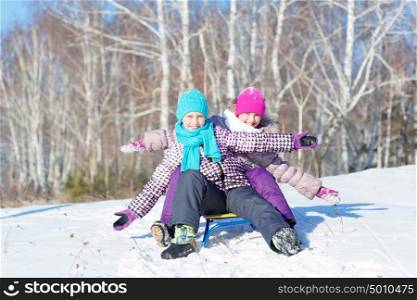 Winter fun. Two cute girls enjoying sledge ride in beautiful snowy winter park