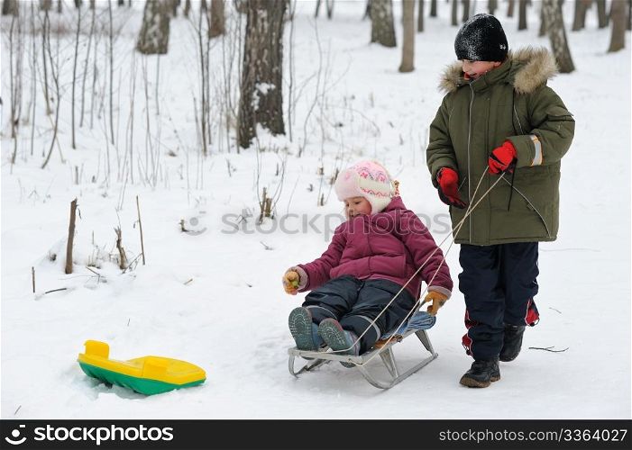 Winter games children - a girl on a sledge and a boy next.