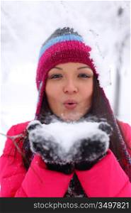 winter girl blow on snow in hands