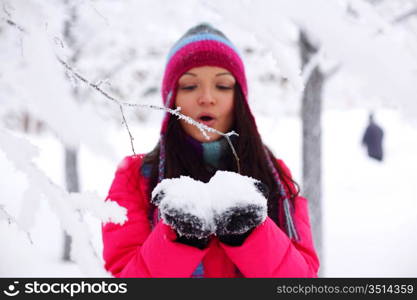 winter girl blow on snow in hands