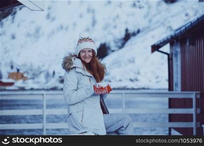 winter. girl with a cup on the background of rorbu on the Lofoten islands. Norway