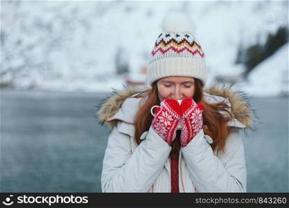 winter. girl with a cup on the background of rorbu on the Lofoten islands. Norway