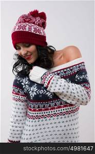 Winter girl, young beautiful woman smiling and dancing wearing red knitted hat and dress over white background