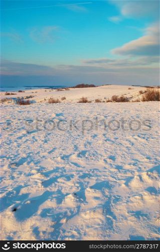 Winter hills covered by snow against sunset