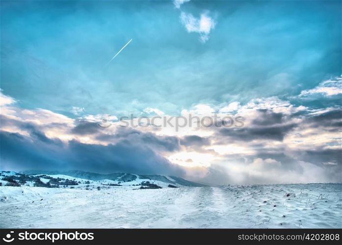 Winter hills covered by snow against sunset