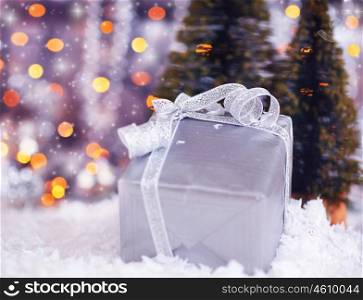 Winter holiday background with present gift box, silver ribbon ornament &amp; Christmas snow decoration &amp; defocus lights