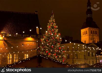 winter holidays and celebration concept - beautiful christmas market in evening at town hall square in tallinn, estonia. christmas market at tallinn old town hall square