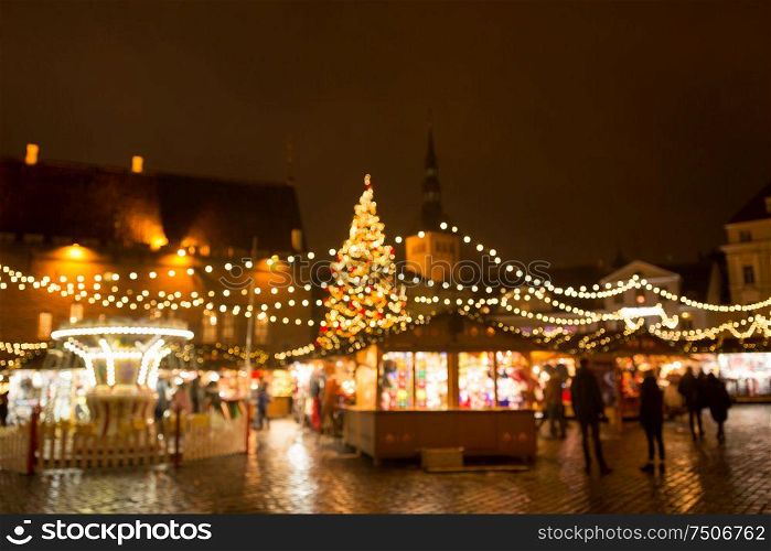 winter holidays and celebration concept - blurred christmas market in winter evening at town hall square in tallinn, estonia. christmas market at tallinn old town hall square