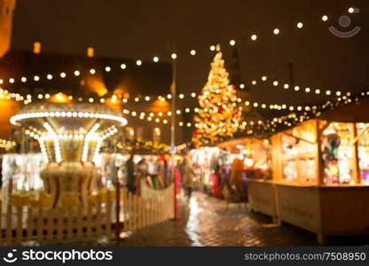 winter holidays and celebration concept - blurred christmas market in winter evening at town hall square in tallinn, estonia. christmas market at tallinn old town hall square