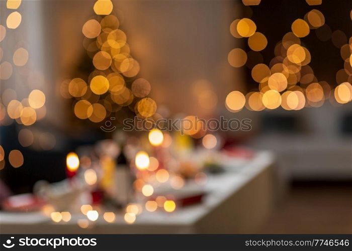 winter holidays and celebration concept - blurred lights and table served for christmas dinner party at home. blurred table serving for christmas party at home
