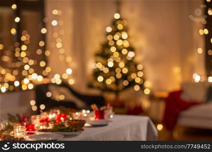 winter holidays and celebration concept - blurred lights and table served for christmas dinner party at home. blurred table serving for christmas party at home