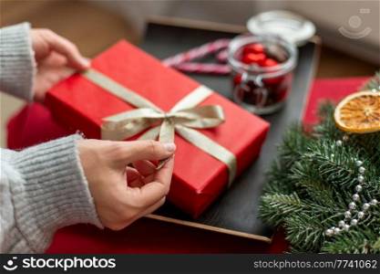 winter holidays and celebration concept - hands with christmas gift, treats and decorations on table at home. hands with christmas gift, treats and decorations