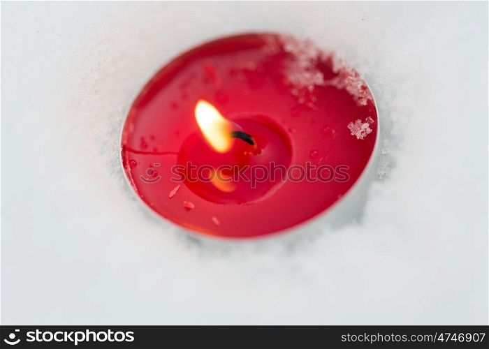 winter holidays and christmas concept - burning christmas candle on snow. burning christmas candle on snow in winter