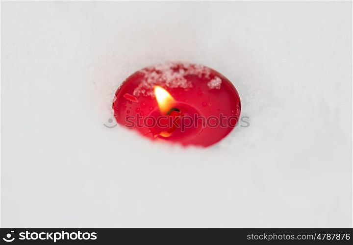 winter holidays and christmas concept - burning christmas candle on snow. burning christmas candle on snow in winter