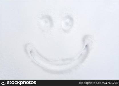 winter holidays and christmas concept - smiley drawing on snow surface. smiley drawing on snow surface