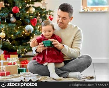winter holidays and family concept - happy middle-aged father and baby daughter with gifts and christmas tree at home. happy father and baby daughter on christmas