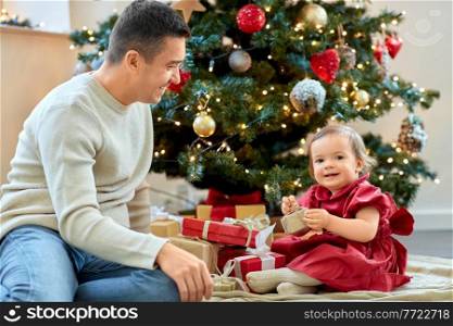 winter holidays and family concept - happy middle-aged father and baby daughter with gifts and christmas tree at home. happy father and baby daughter on christmas