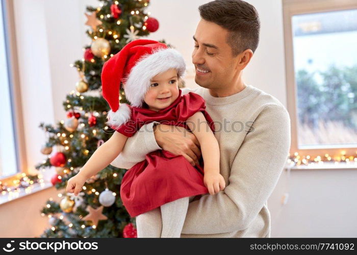 winter holidays and family concept - happy middle-aged father and baby daughter over christmas tree at home. happy father and baby girl over christmas tree