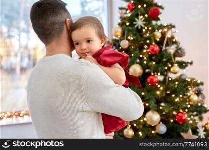 winter holidays and family concept - happy middle-aged father and baby daughter over christmas tree at home. happy father and baby girl over christmas tree