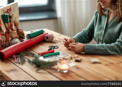 winter holidays and hobby concept - woman with decorated tag making advent calendar on christmas at home. woman making advent calendar on christmas at home