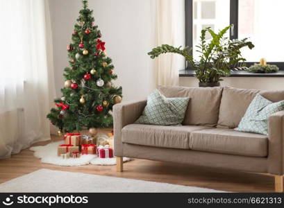 winter holidays and interior concept - christmas tree, gifts and sofa at cozy home living room. christmas tree, gifts and sofa at cozy home