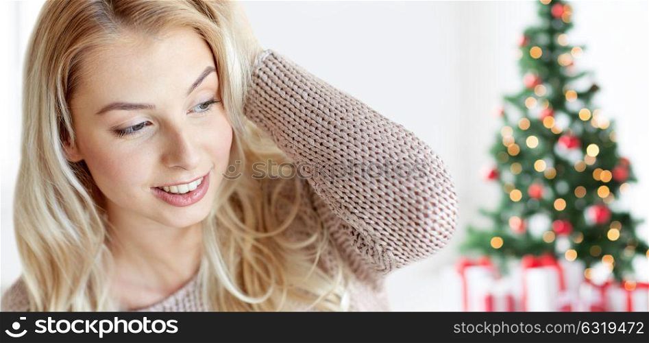 winter, holidays and people concept - close up of happy young woman or teenage girl at home over christmas tree background. happy young woman or teenage girl at christmas