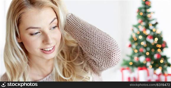 winter, holidays and people concept - close up of happy young woman or teenage girl at home over christmas tree background. happy young woman or teenage girl at christmas