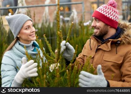 winter holidays and people concept - happy couple buying christmas tree at street market. happy couple buying christmas tree at market