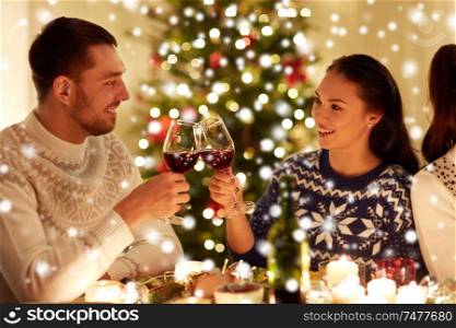 winter holidays and people concept - happy couple celebrating christmas at home feast and drinking red wine over snow. happy couple celebrating christmas at home feast