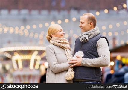 winter holidays and people concept - happy couple over christmas market or amusement park background. happy couple at christmas market