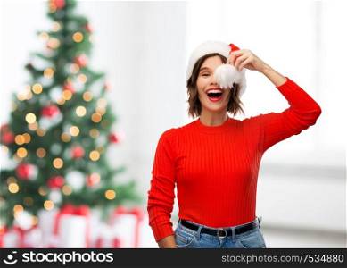 winter holidays and people concept - happy smiling young woman in santa helper hat over christmas tree lights background. happy young woman in santa hat on christmas