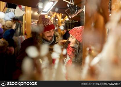 winter holidays and people concept - happy young at christmas market in evening. happy couple at christmas market