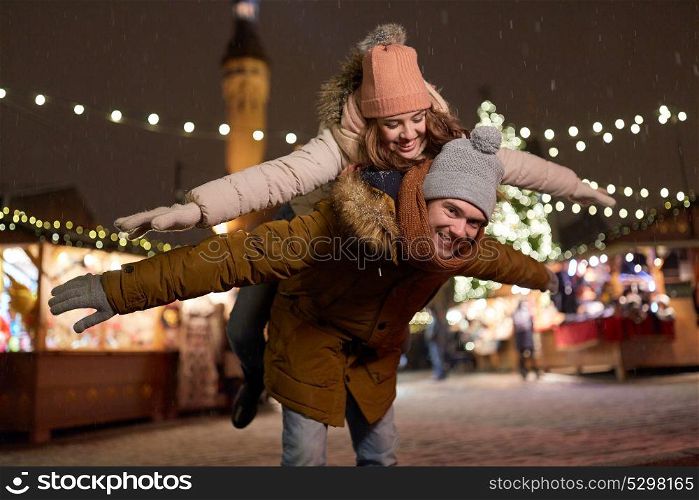 winter holidays and people concept - happy young couple dating and having fun at christmas market in evening. happy couple having fun at christmas market