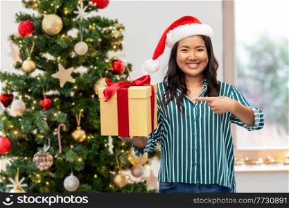 winter holidays and people concept - happy young woman with gift box over christmas tree on background. happy woman with christmas present