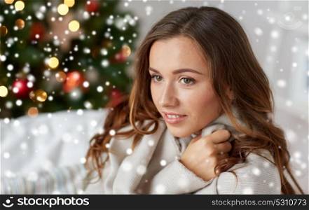 winter holidays and people concept - happy young woman with plaid over christmas tree at home and snow. happy young woman with plaid at home for christmas