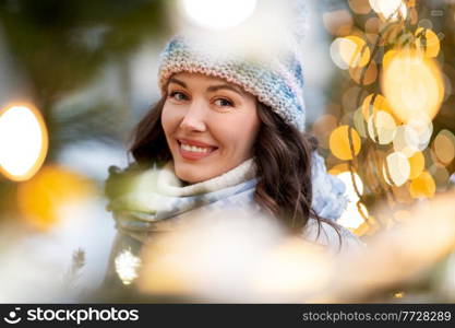 winter holidays and people concept - portrait of happy smiling young woman in christmas lights. portrait of happy young woman in christmas lights