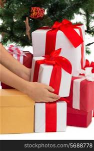winter holidays, celebration and people concept - close up of woman putting present under christmas tree