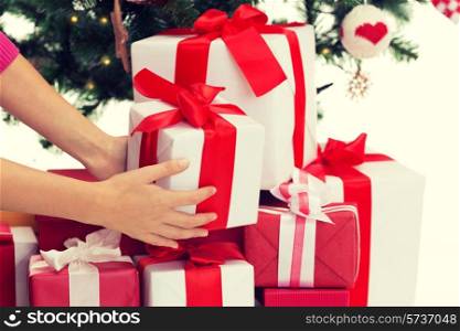 winter holidays, celebration and people concept - close up of woman putting present under christmas tree