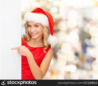winter holidays, christmas, advertising and people concept - smiling young woman in santa helper hat with white blank billboard over lights background