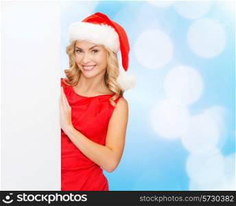 winter holidays, christmas, advertising and people concept - smiling young woman in santa helper hat with white blank billboard over blue lights background