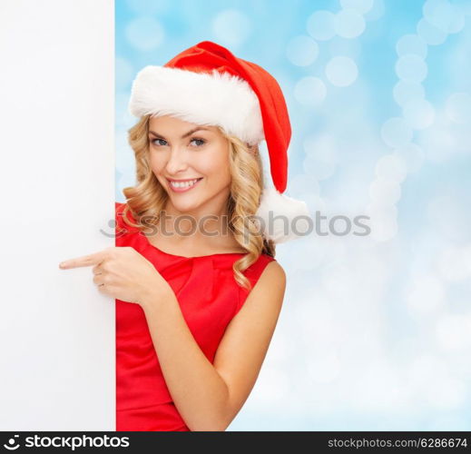 winter holidays, christmas, advertising and people concept - smiling young woman in santa helper hat with white blank billboard over blue lights background