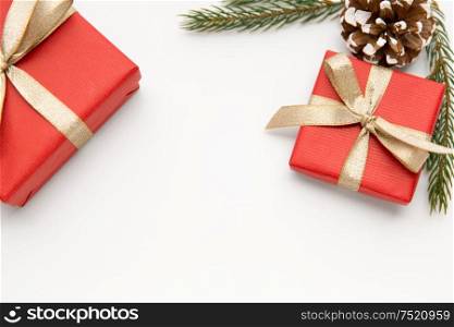 winter holidays, christmas and celebration concept - red gift boxes and fir tree branches with pine cones on white background. christmas gifts and fir branches with pine cones