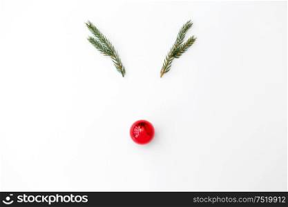 winter holidays, christmas and decorations concept - reindeermade of fir branches and red ball on white background. christmas deer made of fir branches and red ball