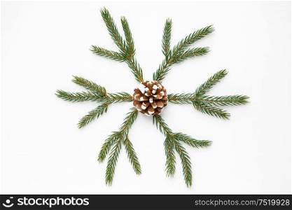 winter holidays, christmas and decorations concept - snowflake shape made of fir branches and pine cone on white background. christmas ornament of fir branches and pine cone